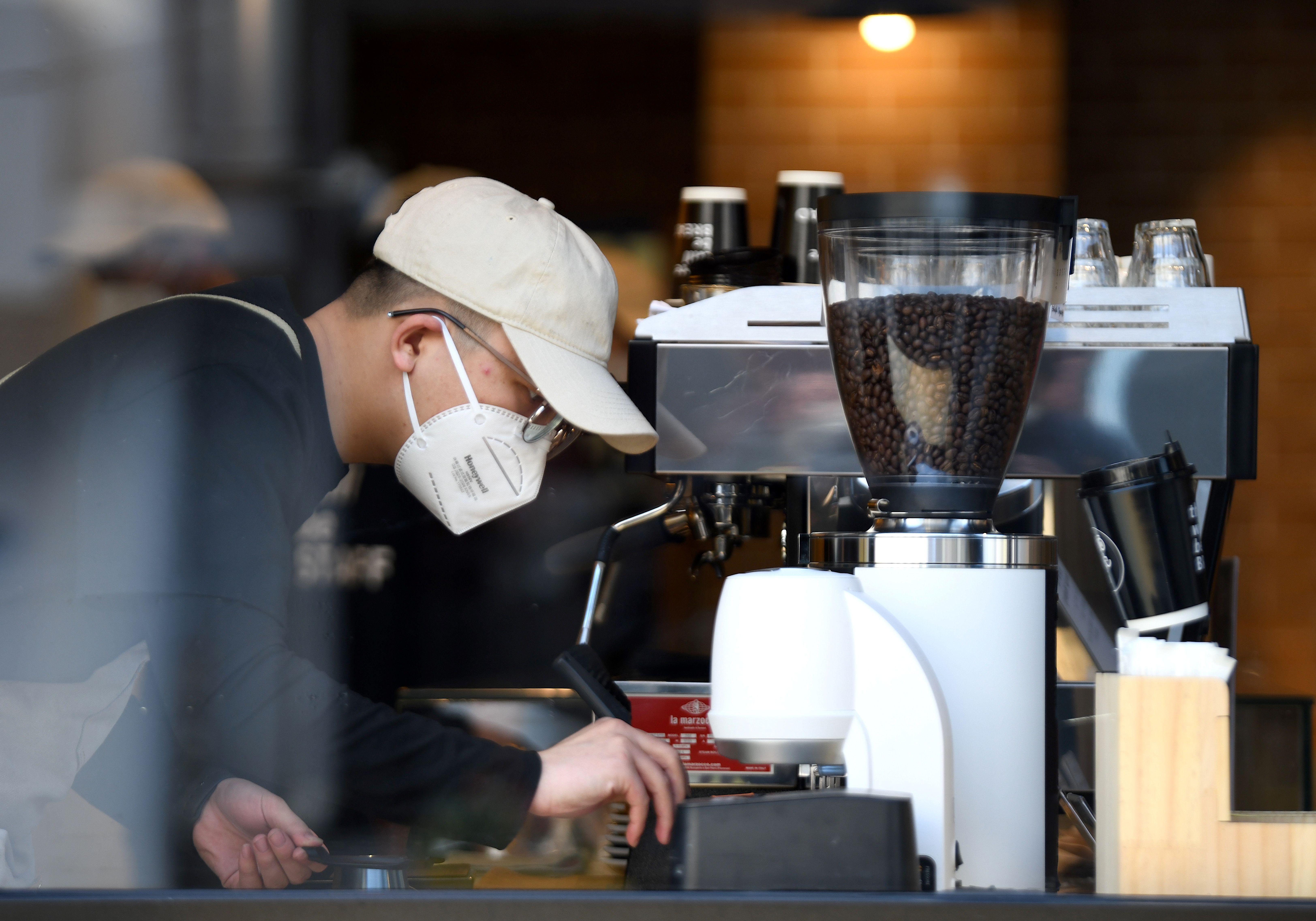 A barista in a Chinese cafe wears a facemask.