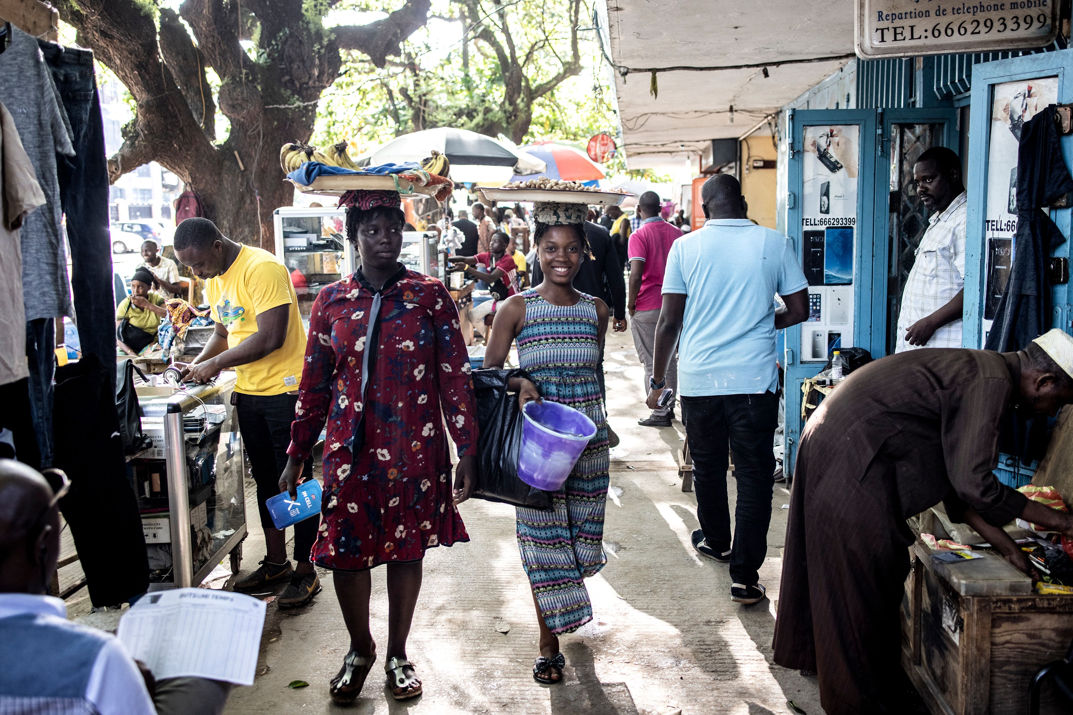 Une fille sourit alors qu'elle marche avec des cacahuètes à vendre à Conakry le 13 septembre 2021