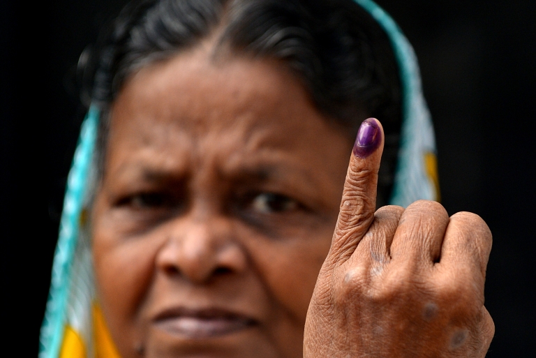 A Sri Lankan woman holds up her inked finger after casting her ballot at a polling station in Colombo on August 17, 2015 