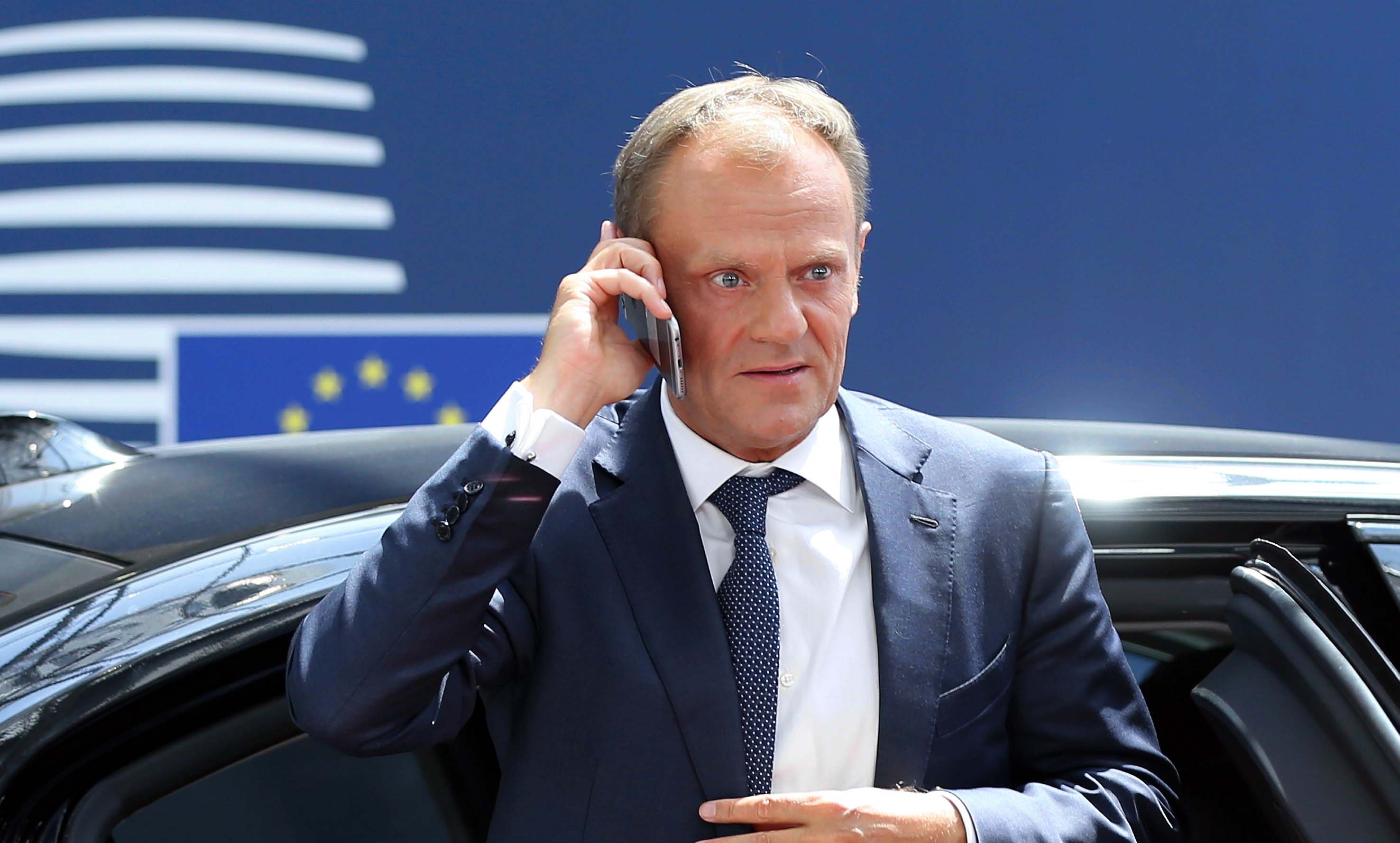 Donald Tusk on the phone at an EU summit