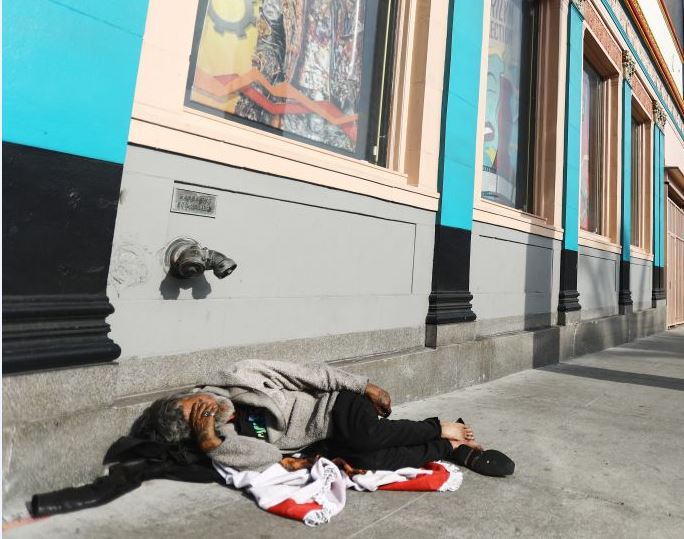 Homeless man lying in street in Los Angeles