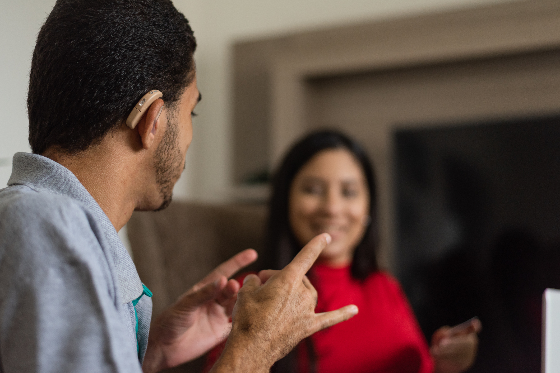 Person with hearing aid  signing to woman