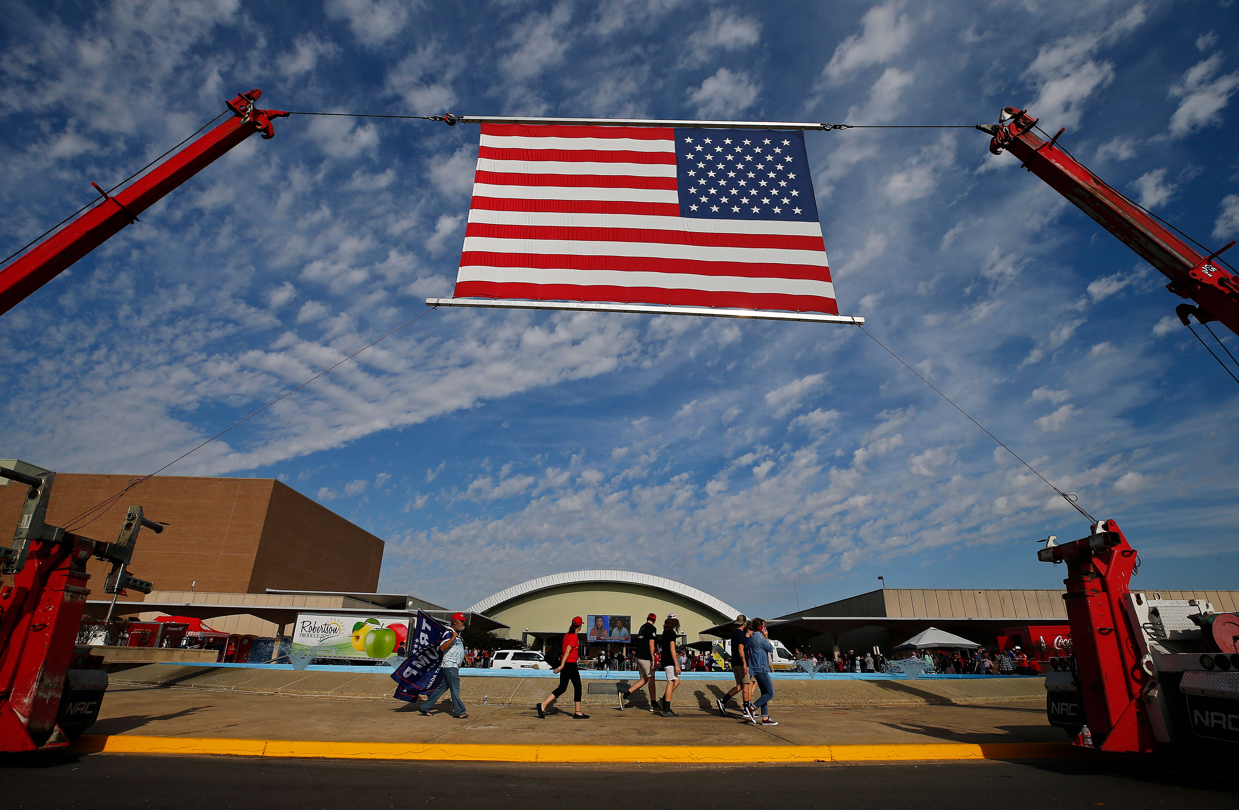 People walk beneath an American flag into a rally to support Donald Trump