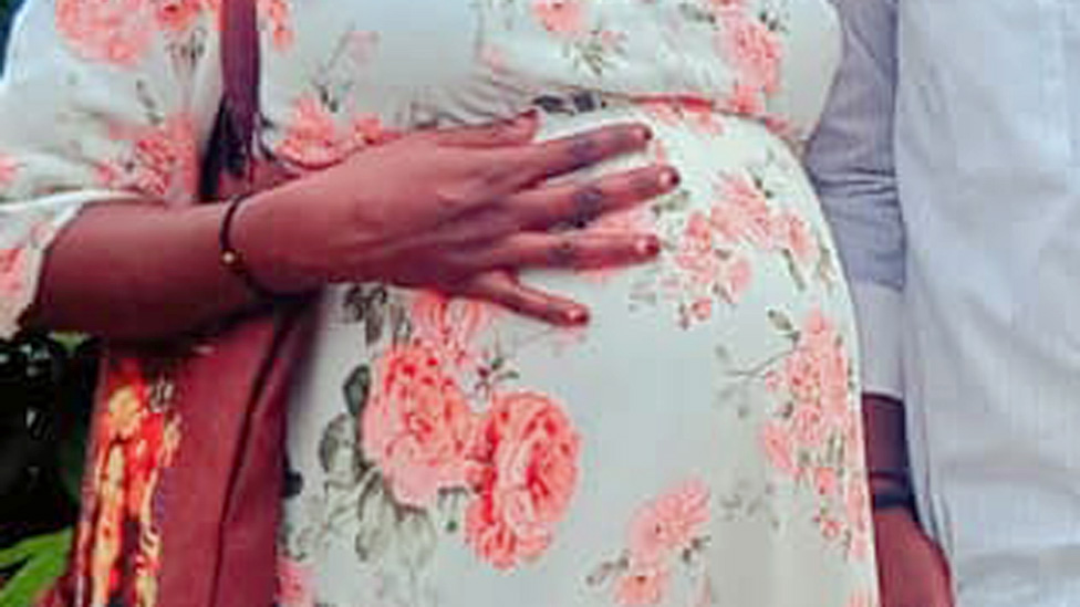 Amira's hand on her pregnant stomach.