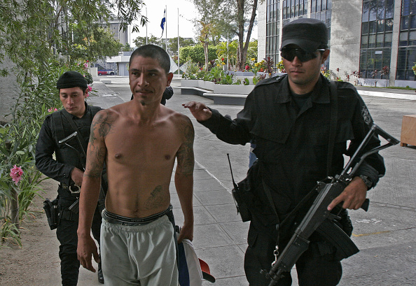 Un presunto criminal acompañado por oficiales policiales. 
