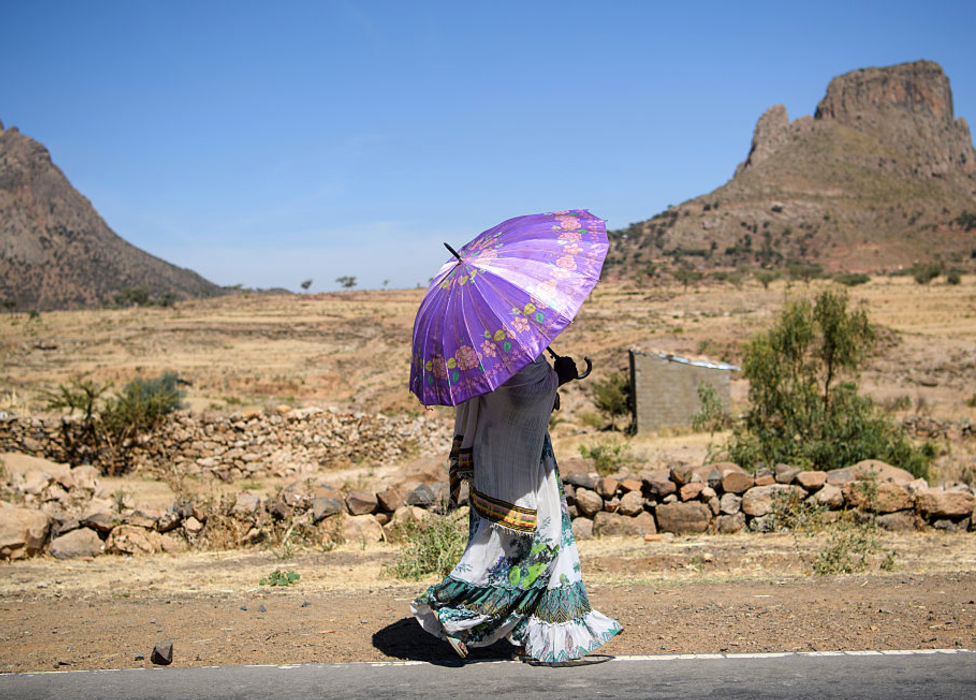 A woman walking with an umbrella along a road in Tigray, Ethiopia