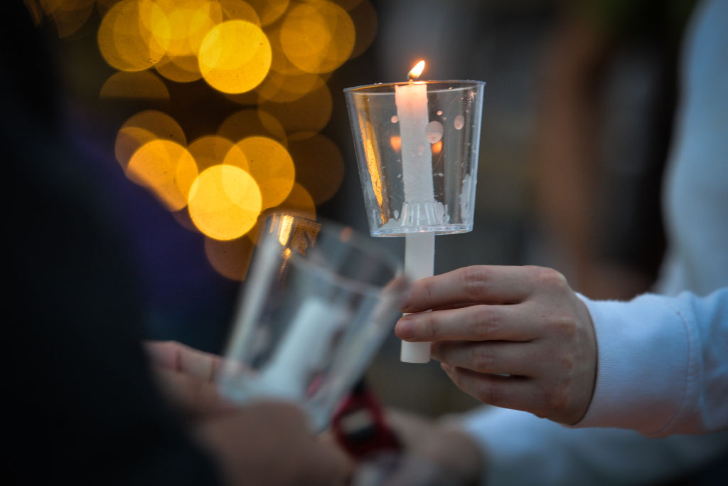 Participants light candles at a candlelight vigil 