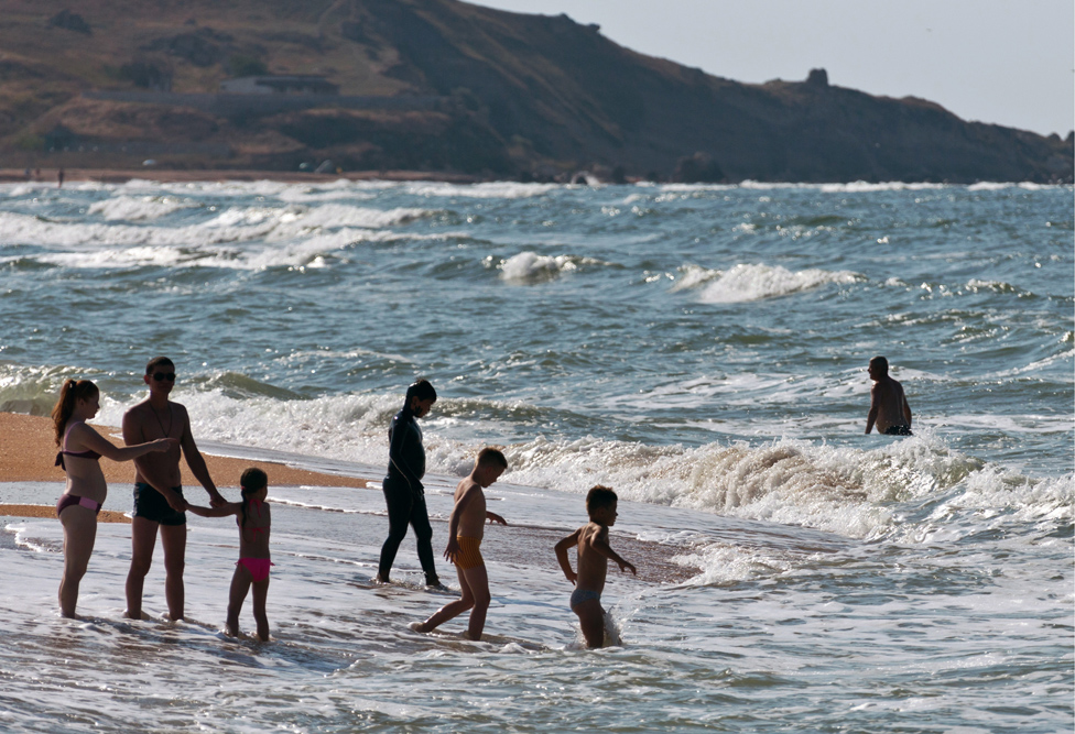 Beach-goers play at the water's edge