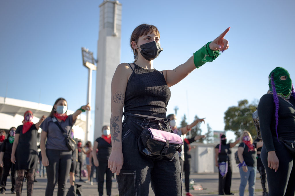 Un hombre frente a un piano y un escritorio levantando los brazos en una expresión de felicidad