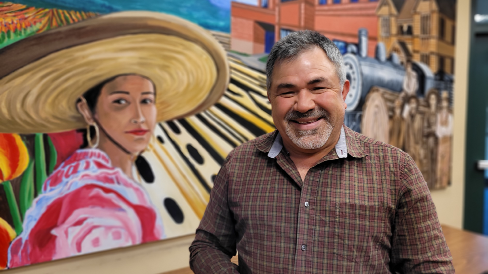 Daniel Quiñones con un mural representativo de Woodburn detrás. 