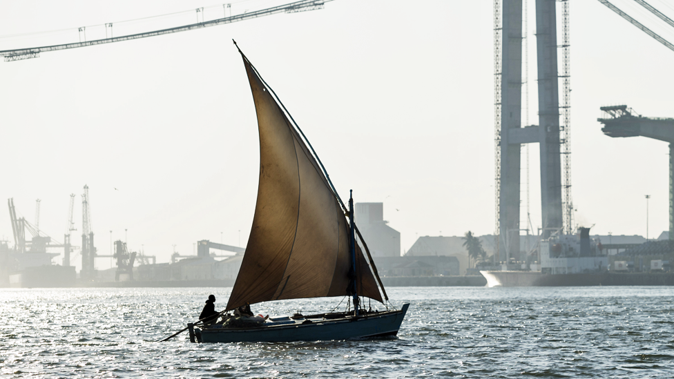 A dhow sailing in front of a Maputo road bridge