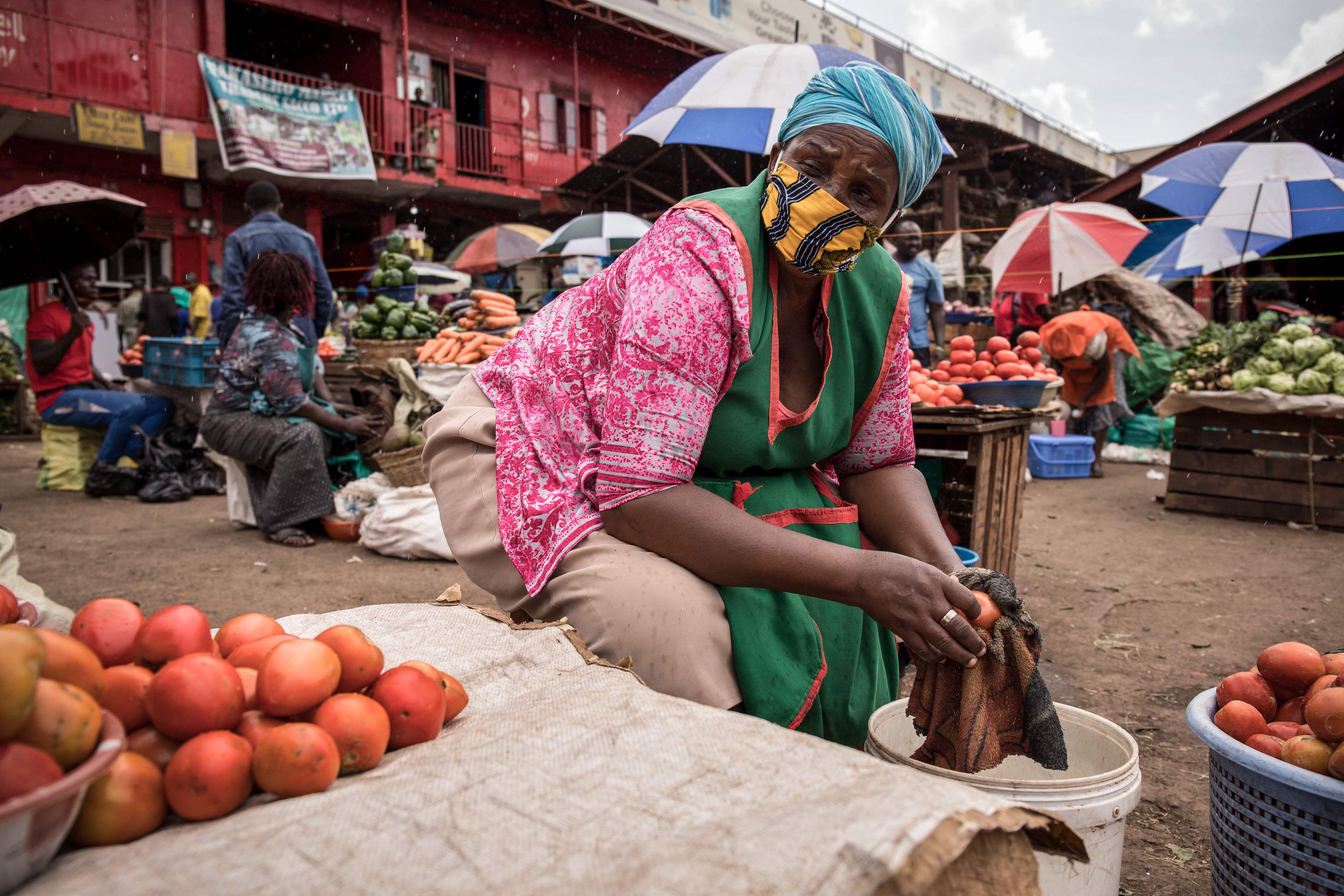 A woman sells tomatoes while wearing a face mask at the Nakasero market in Kampala, Uganda,