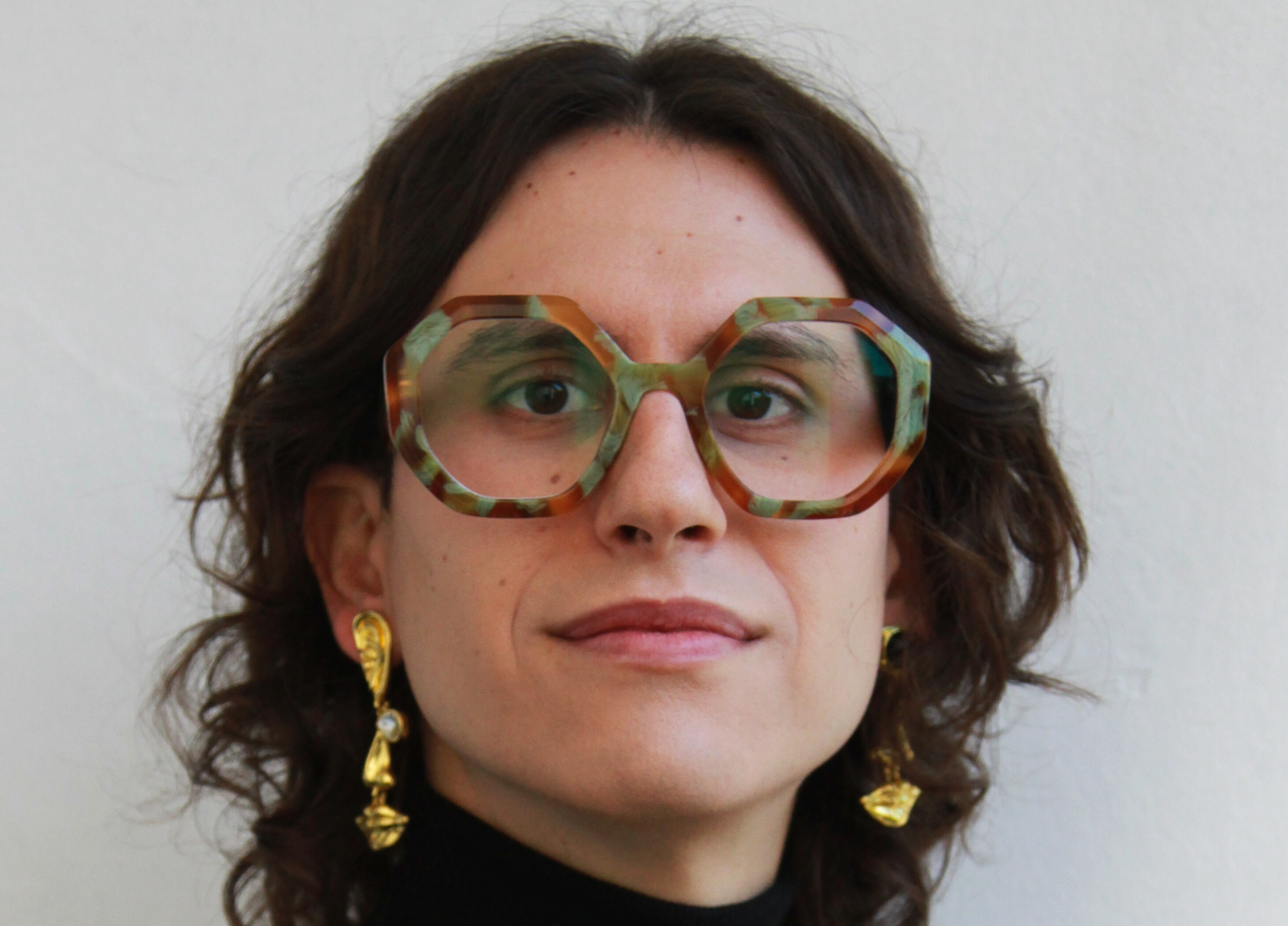 Una mujer con anteojos y aretes dorados
