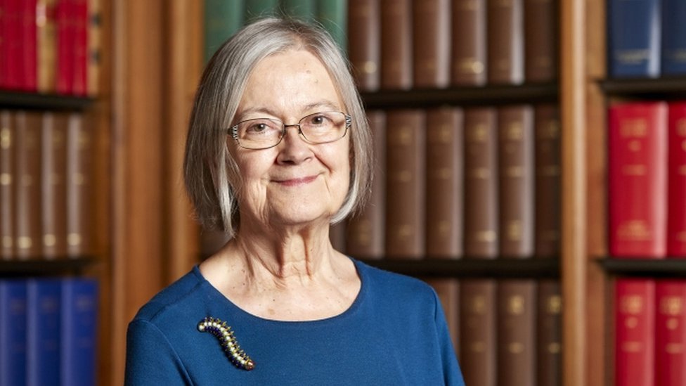 lady hale in front of a bookcase 