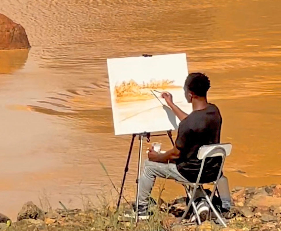 Israel Derrick Apeti painting a river scene