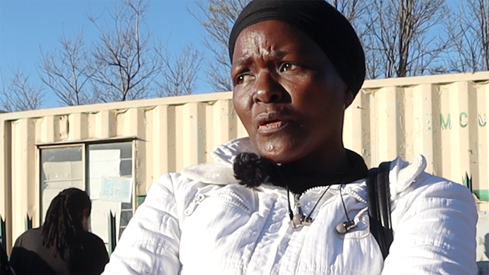 A head and shoulders shot of a woman in a white jacket and black headwrap.