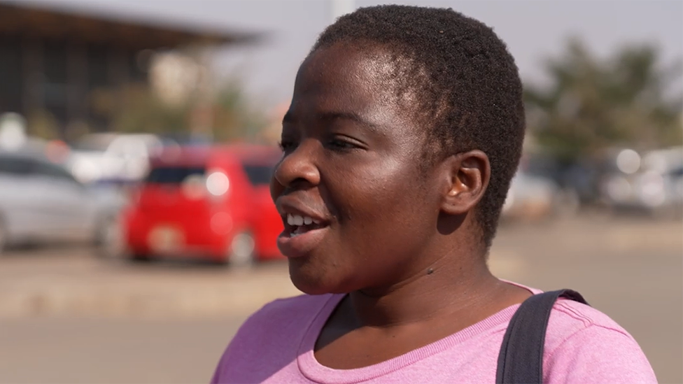 A head shot of a Malawian voter taken on the roadside. She has short hair and is wearing a pink T-shirt.