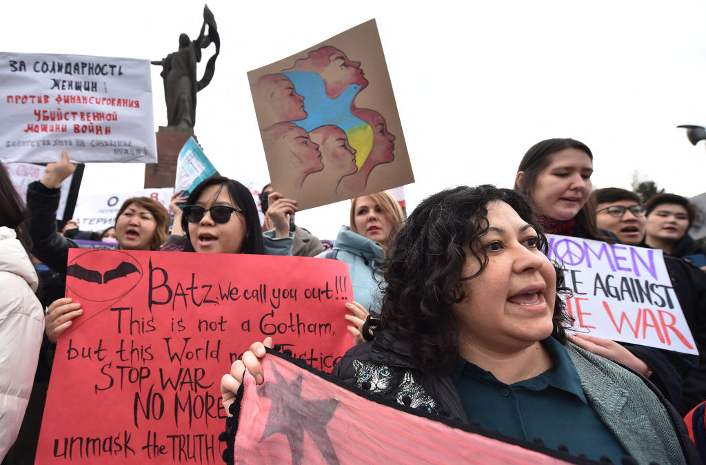 People carry banners and posters, some denouncing Russia's invasion of the Ukraine, as they attend a rally to mark the International Women's Day in Bishkek on March 8, 2022.