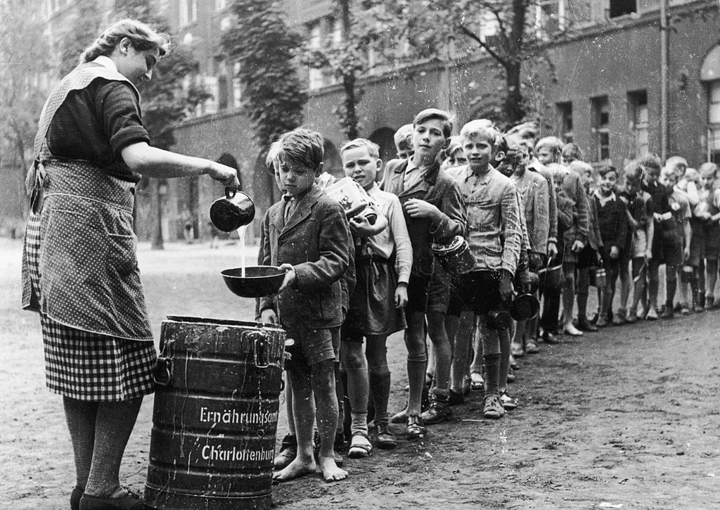 Niños al final de la guerra haciendo cola para tomar leche. 