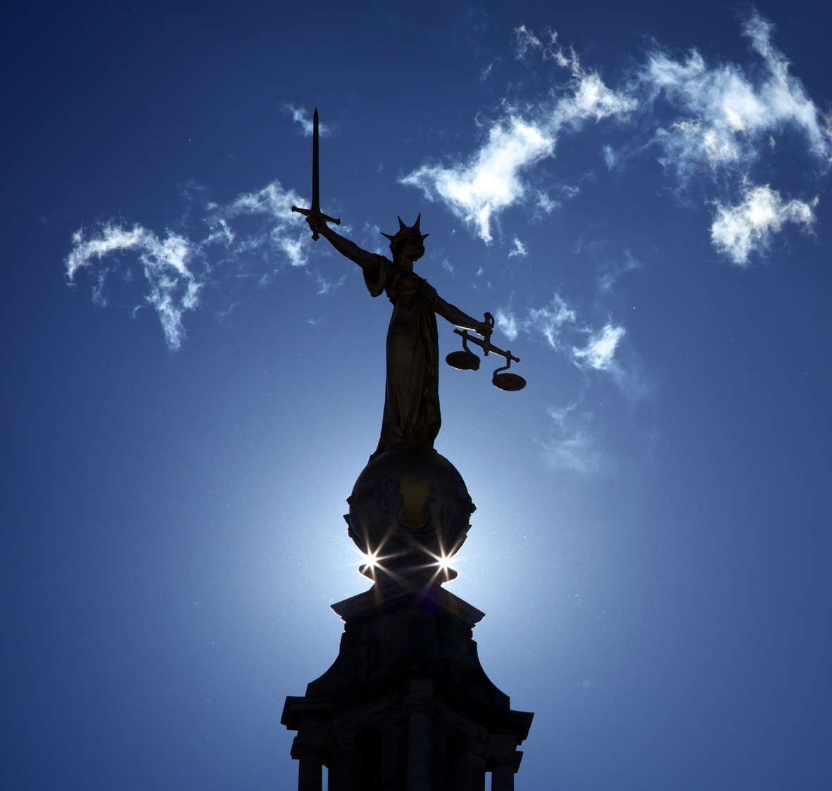 A statue of justice silhouetted against the sky.