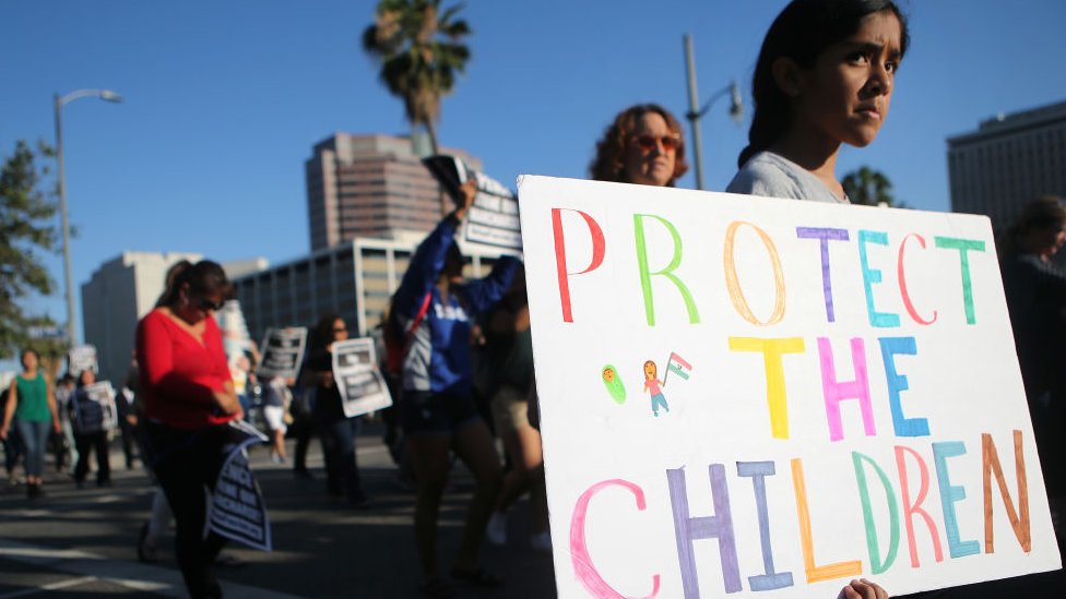 Una niña sostiene una pancarta que dice "Protejan a los niños" durante una protesta en Estados Unidos