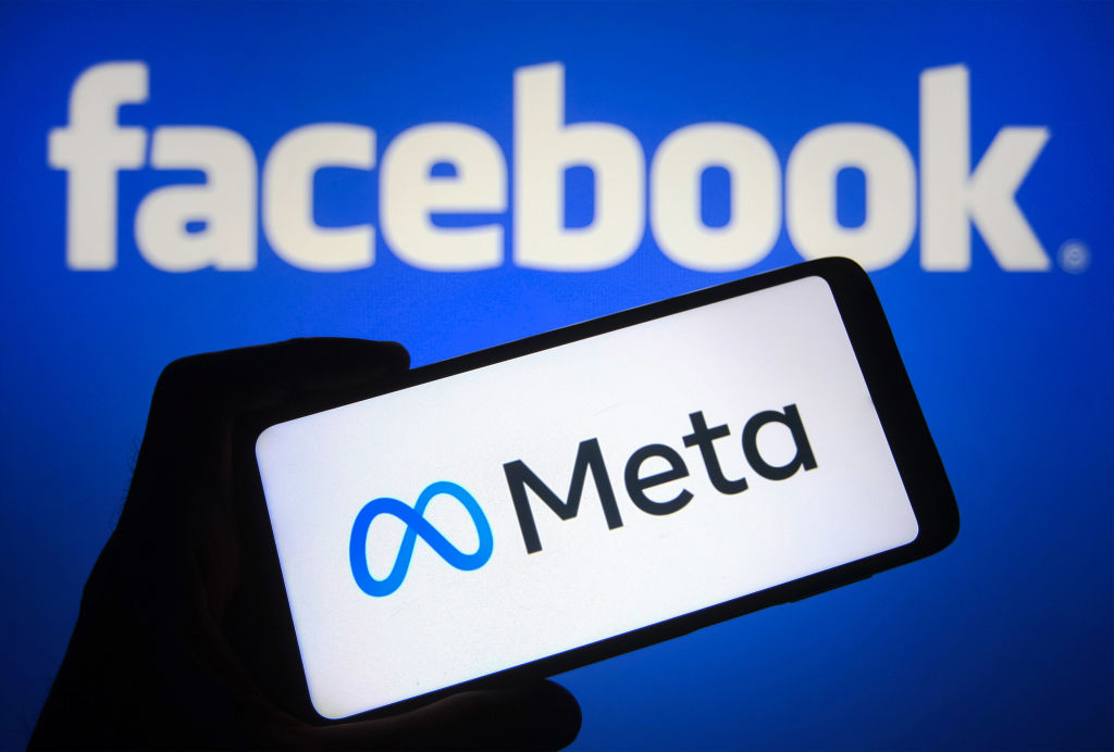 Un móvil con el logo de Meta frente al logo de Facebook