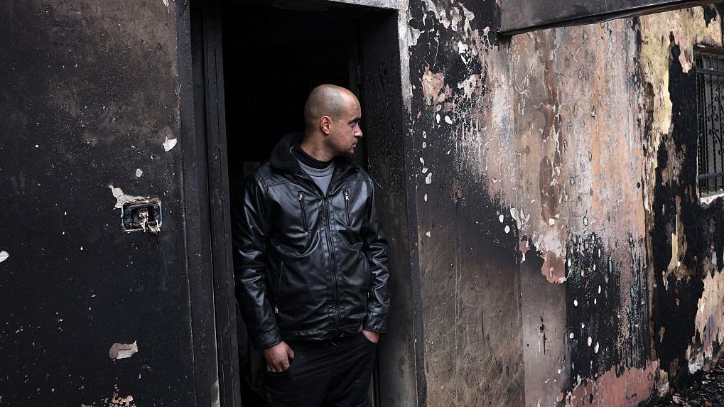 A Palestinian man inspects the remains of his burned family home after a settler attack in the West Bank.